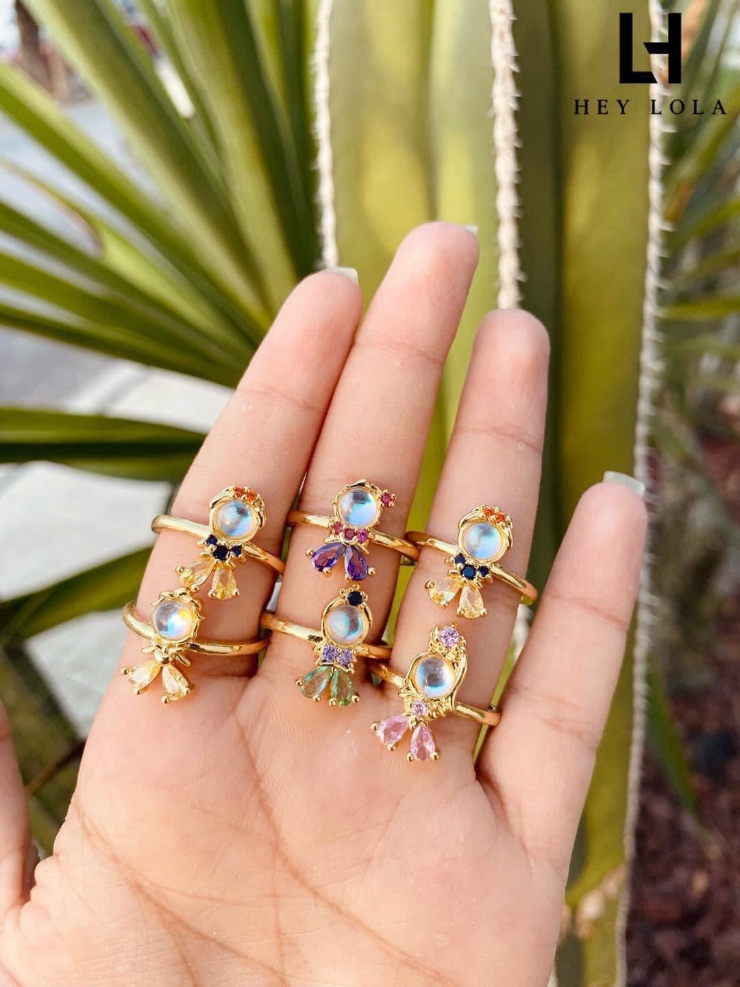 Anillos de fantasía con piedra central iridiscente y gemas de colores