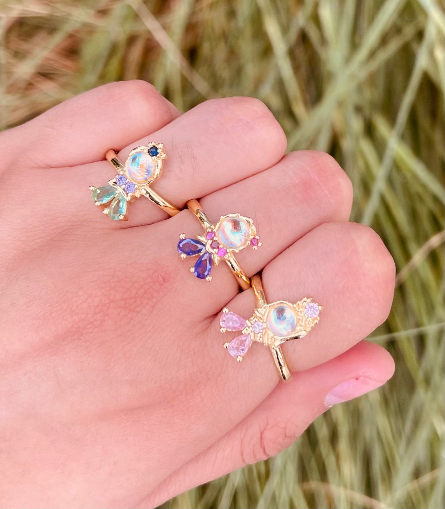 Anillos de fantasía con piedra central iridiscente y gemas de colores