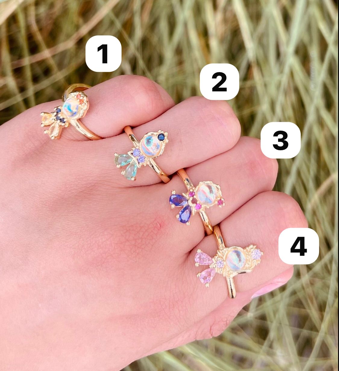 Anillos de fantasía con piedra central iridiscente y gemas de colores