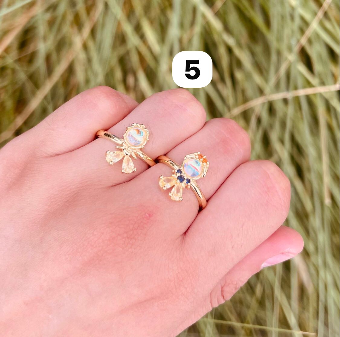 Anillos de fantasía con piedra central iridiscente y gemas de colores
